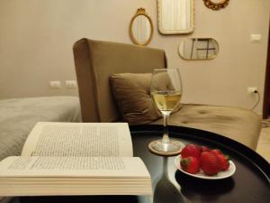 a table with a glass of wine and a book and strawberries at "Cuore Barocco" Hospitality in Noto in Noto