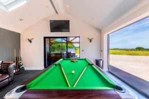 a pool table in a living room with a large window at Greenwood House in Whitegate