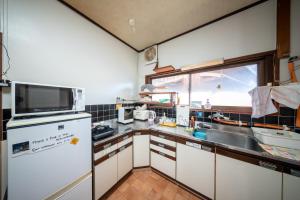 a kitchen with a white refrigerator and a sink at Guesthouse SHELL in Naoshima
