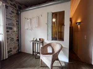 a wicker chair in a room with a table and a window at Le Petit Moras in Chomérac