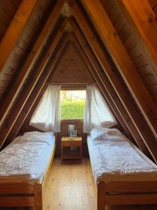two beds in a attic room with a window at Ferienhaus Finnhütte in Zinnowitz