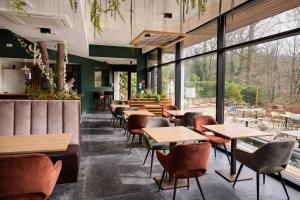 a restaurant with wooden tables and chairs and windows at Utopia Village - Art & Nature Lodges in Mons