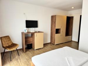 a room with a bed and a desk with a television at Senin Vama Veche in Vama Veche