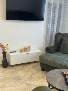 a living room with a couch and a tv on a wall at Apartmani Iman in Medulin