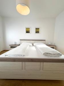 a bedroom with a large white bed with a light above it at Seelavie in Podersdorf am See +32 photos