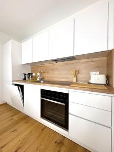 a kitchen with white cabinets and a black oven at Seelavie in Podersdorf am See