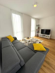 a living room with a gray couch and yellow pillows at Seelavie in Podersdorf am See