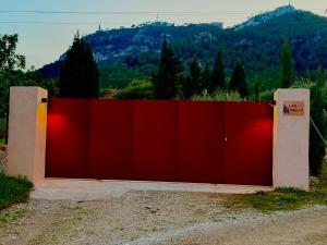 a red fence with a mountain in the background at Finca CanFirella Portocolom in Felanitx