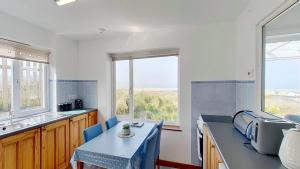 a kitchen with a table and two chairs and windows at C35 Le Grace, Riviere Towans in Hayle