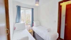 two beds in a room with a window at C35 Le Grace, Riviere Towans in Hayle