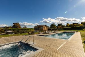 a swimming pool with a wooden deck and a house at Borgo Malvasia- La Quercia in Sasso Marconi