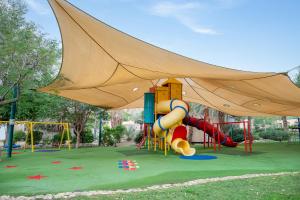 a park with a playground with a large tent at כפר נופש קלי"ה ים המלח in Kalia +47 photos