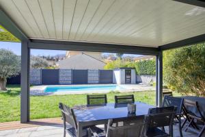 a patio with a table and chairs and a pool at Superbe Villa, 4 chambres, parking, garage et piscine in Genas