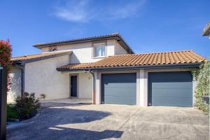 a house with two garage doors in a driveway at Superbe Villa, 4 chambres, parking, garage et piscine in Genas