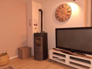 a living room with a television and a clock on the wall at Cozy countryside apartment in Moriville