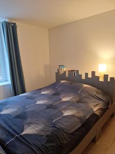 a bedroom with a bed with a blue comforter at Cozy countryside apartment in Moriville