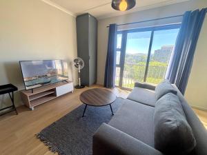 a living room with a couch and a large window at Cape Mae Apartment Hotel in Cape Town