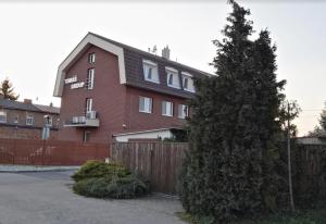 a red brick house with a fence and a tree at Penzion U Tomáše in Ratíškovice