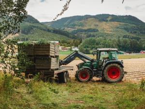 a green tractor pulling a trailer with a barrel at Idylliske Evjua ved Mjøsa in Skreia