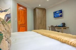 a bedroom with a bed and a wooden door at Apple Blossom Hotel Portfolio in Roodepoort +81 photos