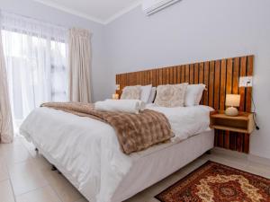 a bedroom with a large bed with a wooden headboard at Lady Daisy Boutique Guesthouse in Rustenburg
