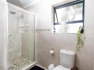a bathroom with a toilet and a glass shower at Lady Daisy Boutique Guesthouse in Rustenburg