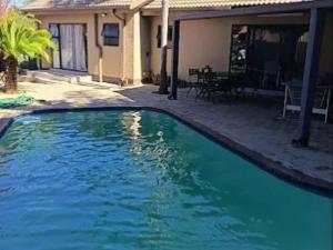 a blue swimming pool in front of a house at Lady Daisy Boutique Guesthouse in Rustenburg