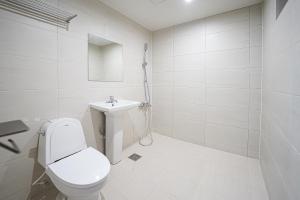 a white bathroom with a toilet and a sink at Midpoint Guesthouse in Busan +7 photos