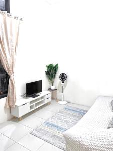 a white bedroom with a bed and a tv at Ibiza house pangandaran in Pangandaran +7 photos
