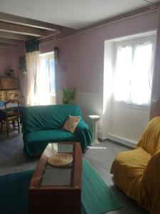 a living room with a green couch and a table at Maison proche centre Les Vans in Les Vans