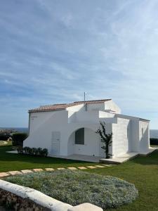 a white house with a grass yard in front of it at Binilua in Binibeca +5 photos