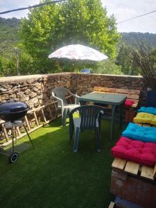 a patio with a table and chairs and an umbrella at Maison proche centre Les Vans in Les Vans +2 photos