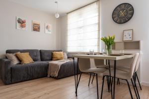 a living room with a couch and a table and a clock at Apartament Daisy Pszczyna Centrum in Pszczyna