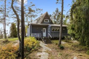 a gray house with a porch in the woods at Trekanthytte in Moss