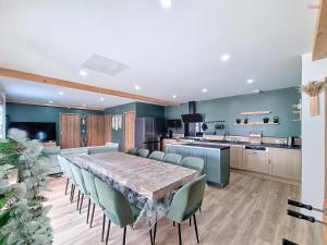 a dining room with a long table and green chairs at Les Piafs du Der 2 in Joncreuil