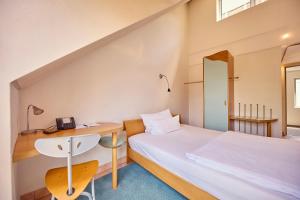 ein kleines Schlafzimmer mit Bett und Schreibtisch in der Unterkunft Hotel Watthalden in Ettlingen + 141 Fotos