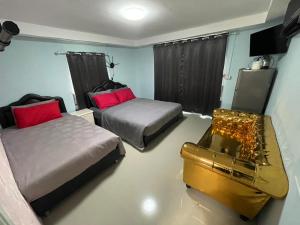 a bedroom with two beds and a bench in it at บ้านมาดาม เขาใหญ่ in Pak Chong
