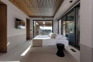 a bedroom with a white bed and a large window at Crimson View Villa by Hide Out in Ios Chora