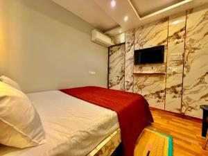 a bedroom with a bed and a tv on a wall at Bengal Guest House in Howrah