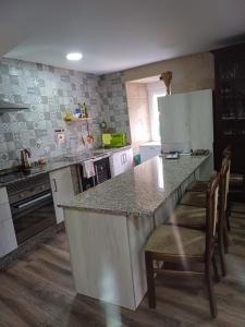 a kitchen with a counter and a kitchen island with chairs at O Cobo Vacacional in Padrón