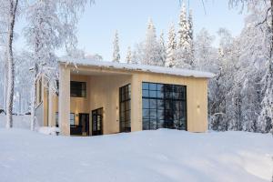 a building in the snow with snow covered trees at Taikavilla in Kuusamo