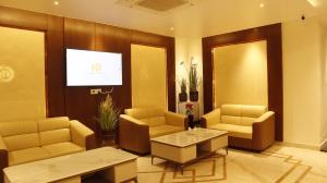 a lobby with a waiting room with couches and a tv at Narmada Residency in Hubli