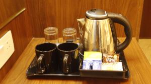 a tray with a tea kettle and cups on a table at Narmada Residency in Hubli