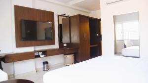 a room with a tv and a mirror and a bed at Narmada Residency in Hubli