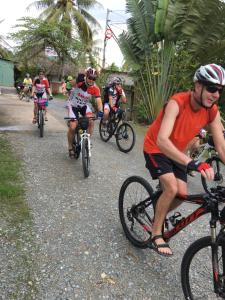 a group of people riding bikes down a road at Aurora Mekong Hotel in Cai Be