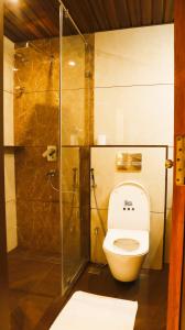 a bathroom with a toilet and a glass shower at Narmada Residency in Hubli +7 photos