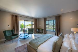 a bedroom with a large bed and two chairs at Khaya Elihle Guest House in Hazyview +35 photos