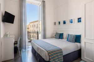 a bedroom with a bed and a large window at Archimede Charm B&B - Historical Palace in Ortigia in Syracuse