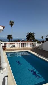 a blue swimming pool with a white fence and palm trees at Holiday Feel - La Orotava in La Orotava