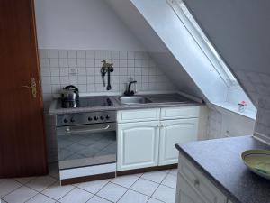 a kitchen with a stove and a sink and a staircase at Gemütliche Ferien oder Monteurs Wohnung in Wallsbüll
